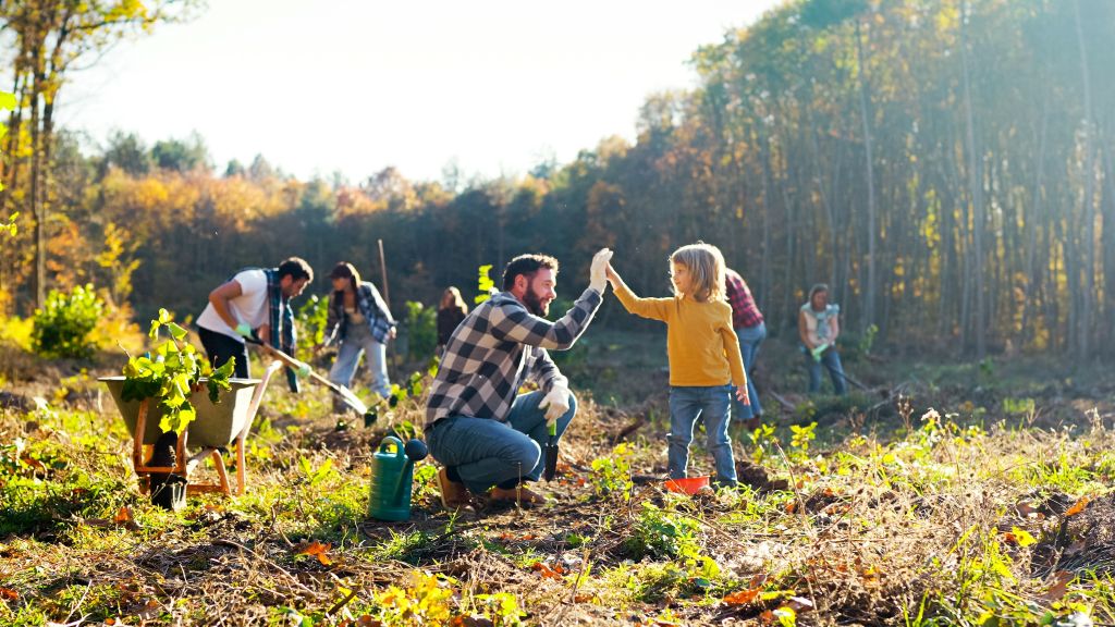 Kleiner Bub hilft seinem Vater und einer Gruppe bei Arbeiten im Wald.