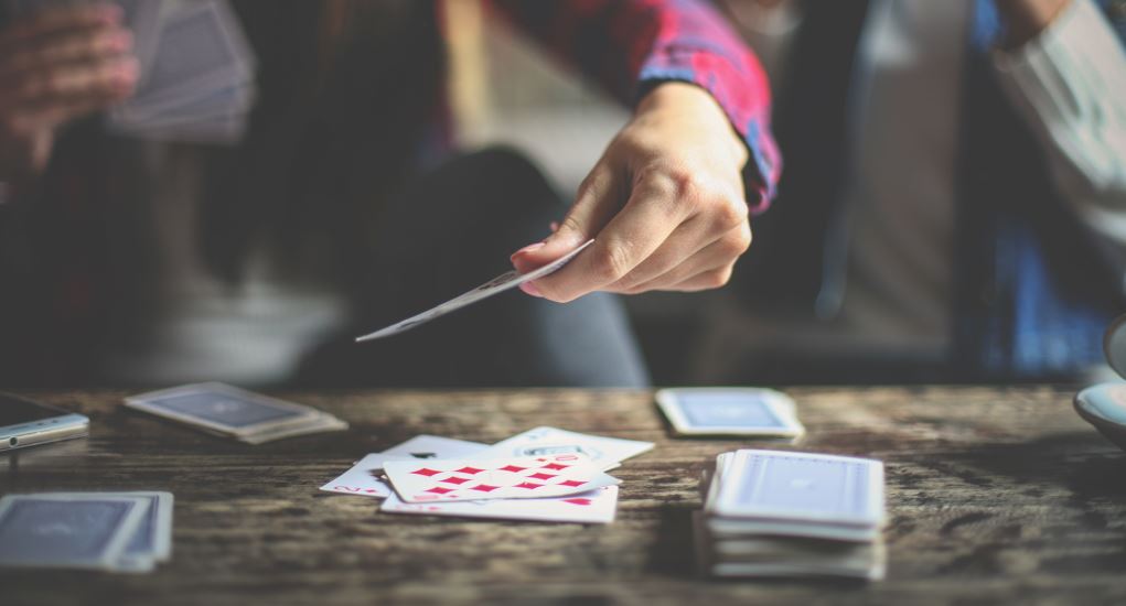 Ein Kartenspiel, bei dem gerade eine Karte auf den Tisch abgelegt wird.