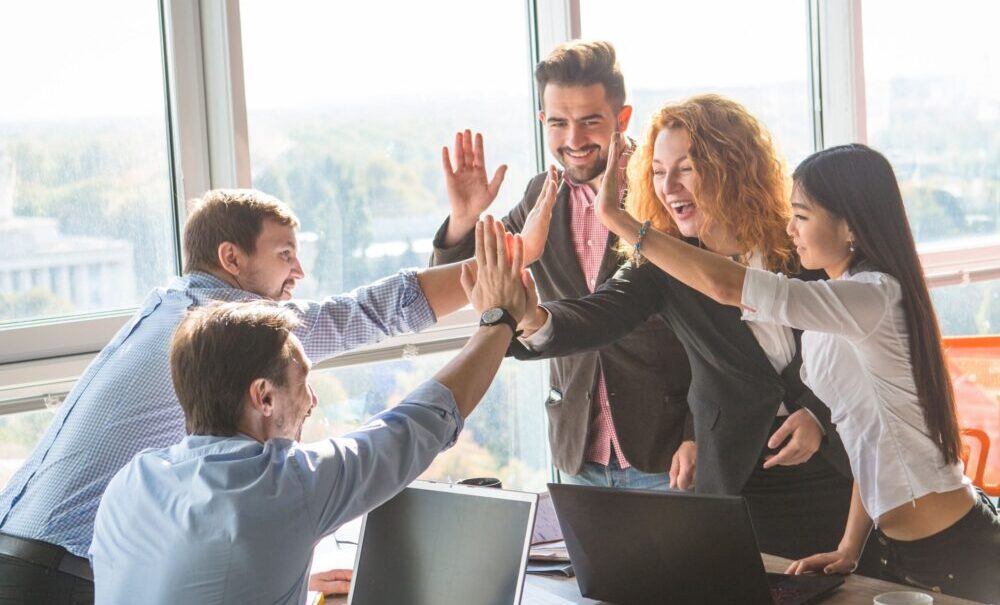 Eine Gruppe von Kollegen, die sich alle gleichzeitig ein High-Five geben